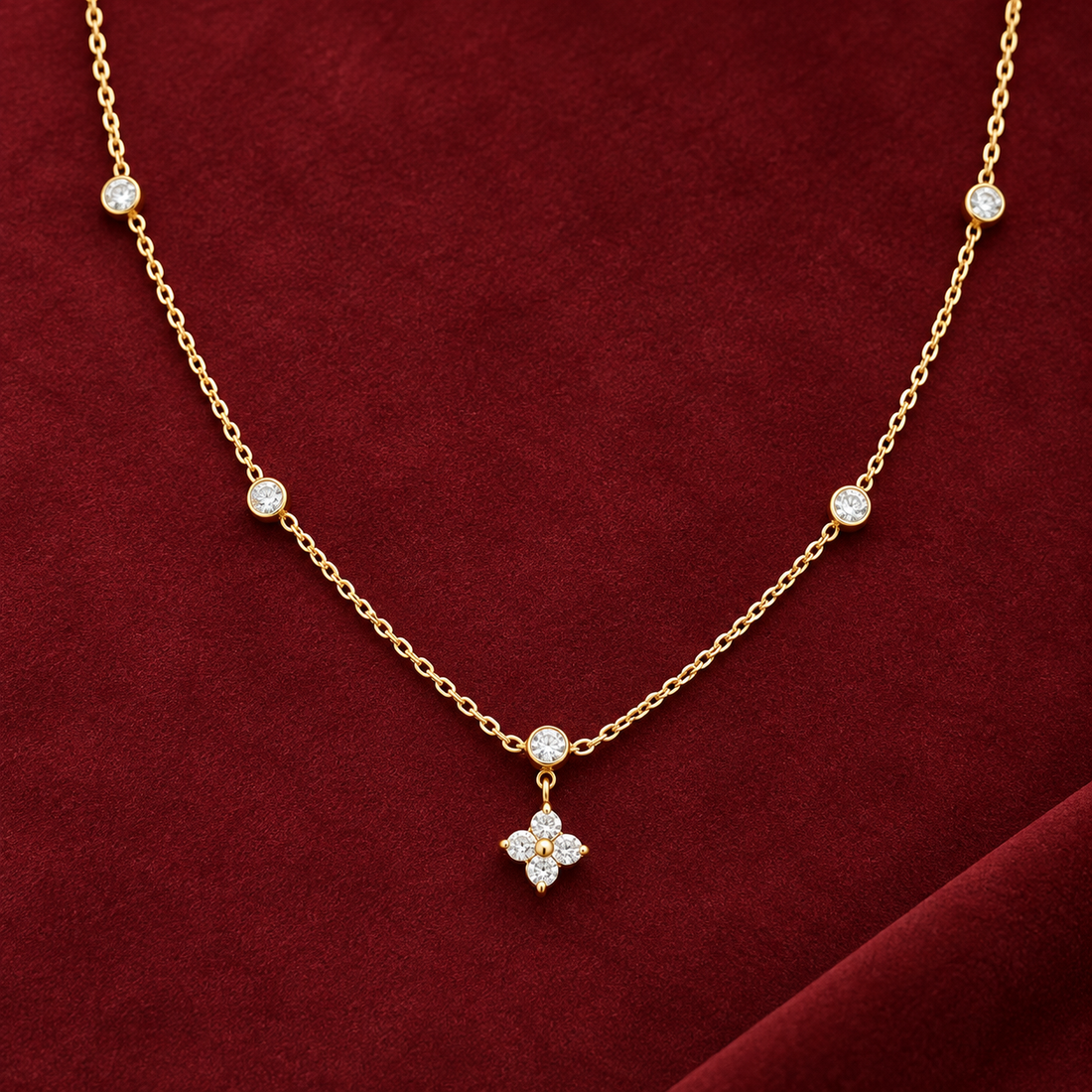 Gold-tone 316L stainless steel necklace with a fine chain, bezel-set crystals along its length and a four-stone flower pendant, shown laid flat