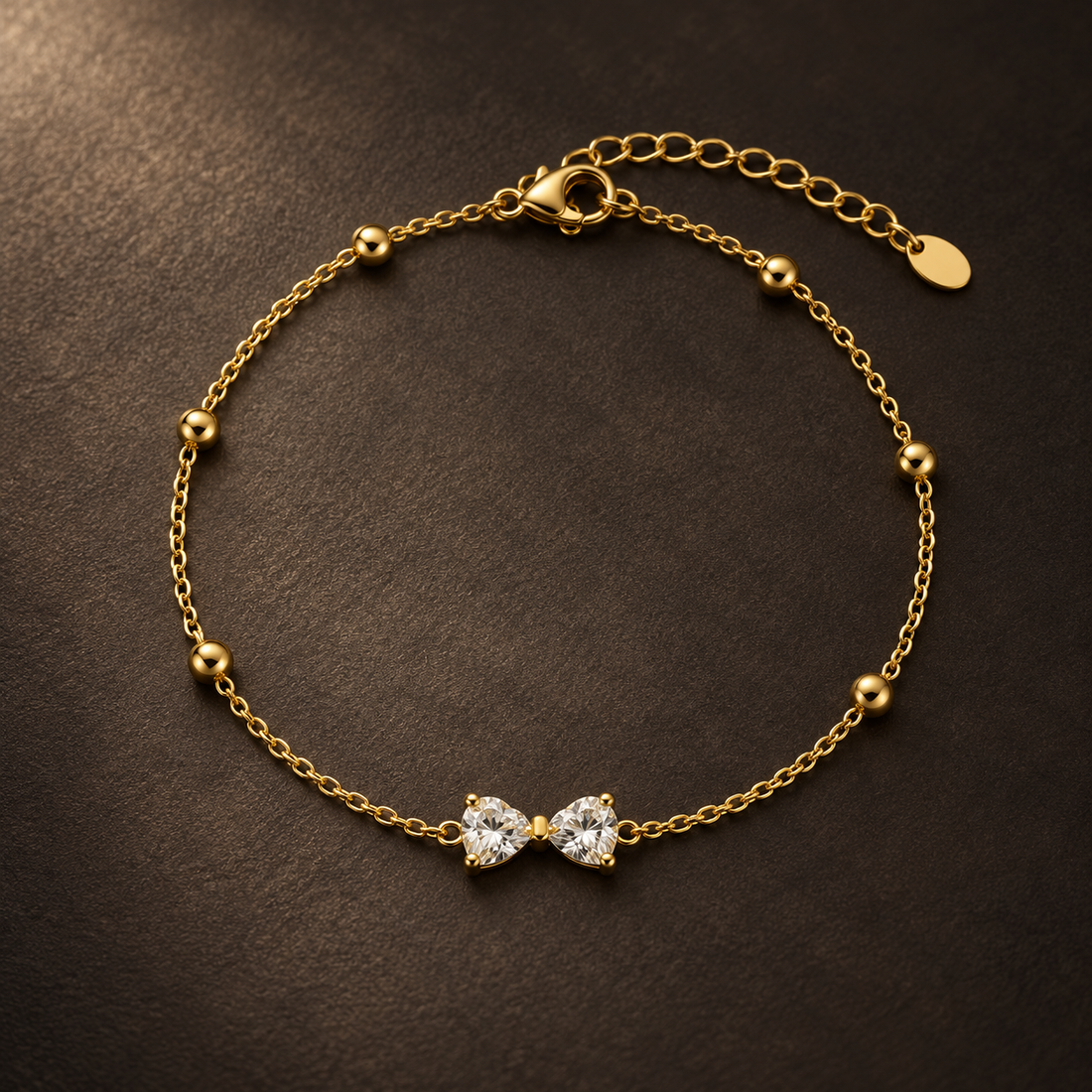 Gold-tone 316L stainless steel chain bracelet with round beads and a centre pair of heart-cut clear stones, laid flat with an extender chain