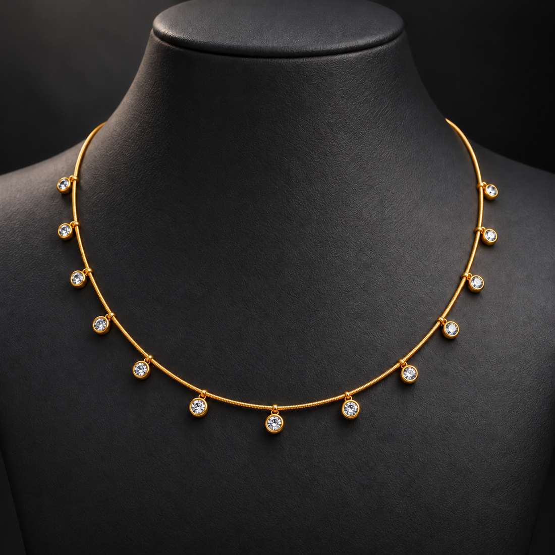 Gold-tone 304 stainless steel necklace with a round snake chain and clear stones in bezel settings hanging at intervals, worn on a dark bust