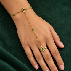 Gold-tone 304 stainless steel hand chain with starburst motifs and green stones, linked to a ring on a hand, worn view