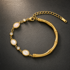 One gold-toned chain bracelet with a polished finish. It is a single-strand flexible piece: one half is a fine oval-link chain of small gauge carrying alternating bezel-set stations, and the other half is a solid curved bamboo-segmented bar forming a rigid section, connected at both ends by small jump rings. The total chain run is approximately twelve times the width of the largest oval component; the extender chain is roughly one third of the main chain length. A working lobster clasp is visible.