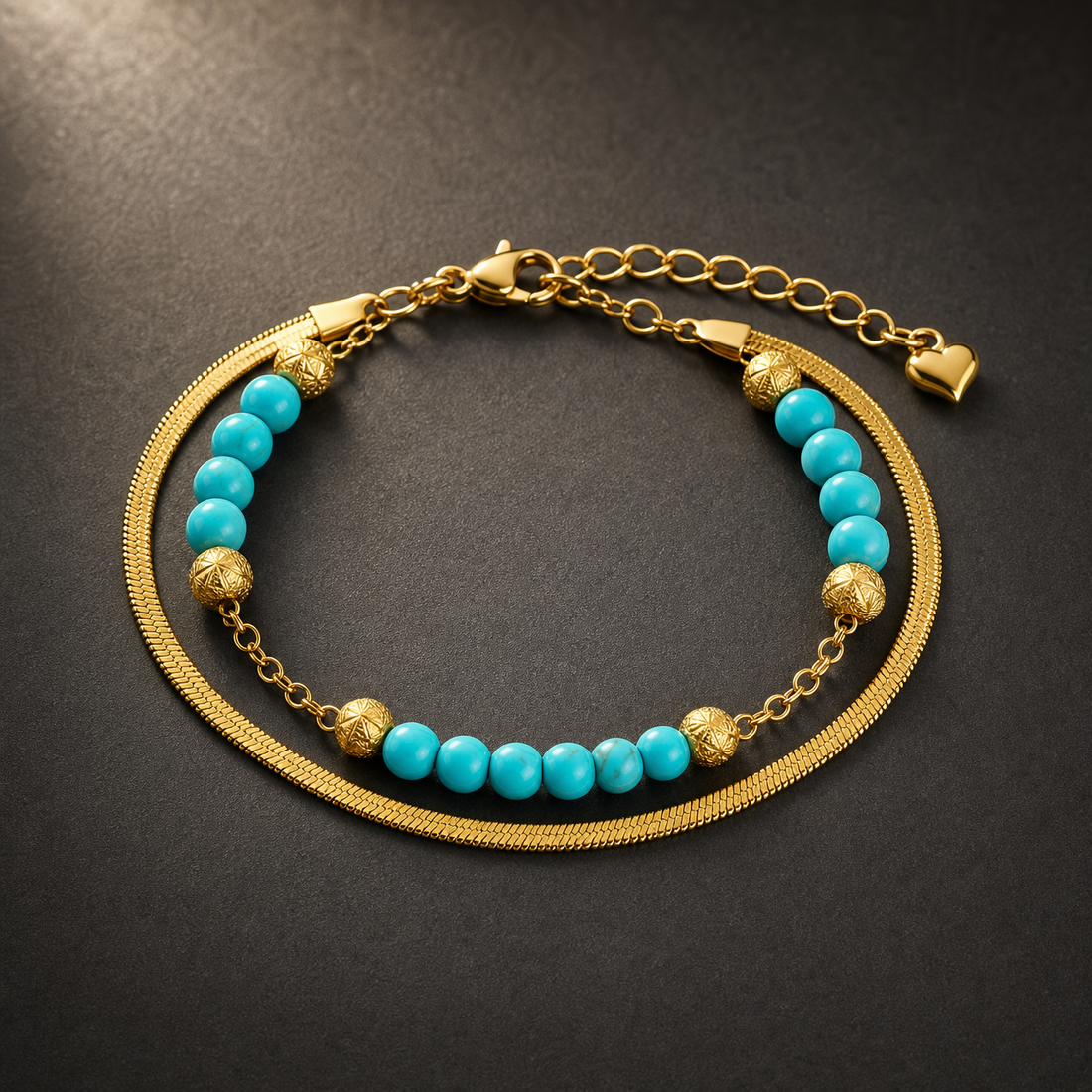 One wrist-worn chain bracelet in yellow-gold-toned metal with a polished finish. It has two parallel strands joined at common end terminals: one strand is a flat, flexible herringbone (snake) chain of fine gauge with no attached components; the other is a fine cable-link chain strung with beads.