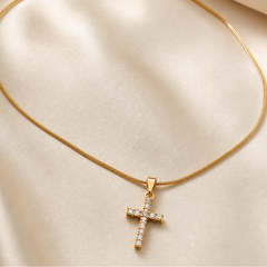 A single pendant necklace in yellow-gold-toned metal with a polished finish. It consists of one continuous single-strand snake chain of fine, tight gauge with a smooth, round cross-section, terminating in a small tapered solid-metal bail from which a single cross pendant hangs via a jump ring.