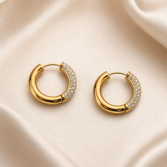 A matched pair of small hoop earrings, two items total, in yellow-gold-toned metal with a high-polish finish. Each earring is a hinged huggie-style hoop of medium-gauge tubular metal forming a continuous ring; a slim straight post at one end swings into a recessed channel at the opposite end, with a small round hinge pin visible on the plain segment.