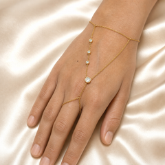 One hand-chain (slave bracelet) in yellow-gold-tone metal with a polished finish, all chain a fine gauge cable chain of small oval links. Starting from the wrist section: a single-strand bracelet chain closes with a lobster clasp; no extender chain or terminal tag is clearly visible. Two chain branches attach to the wrist section at jump rings and cross the back of the hand, converging at a central junction.