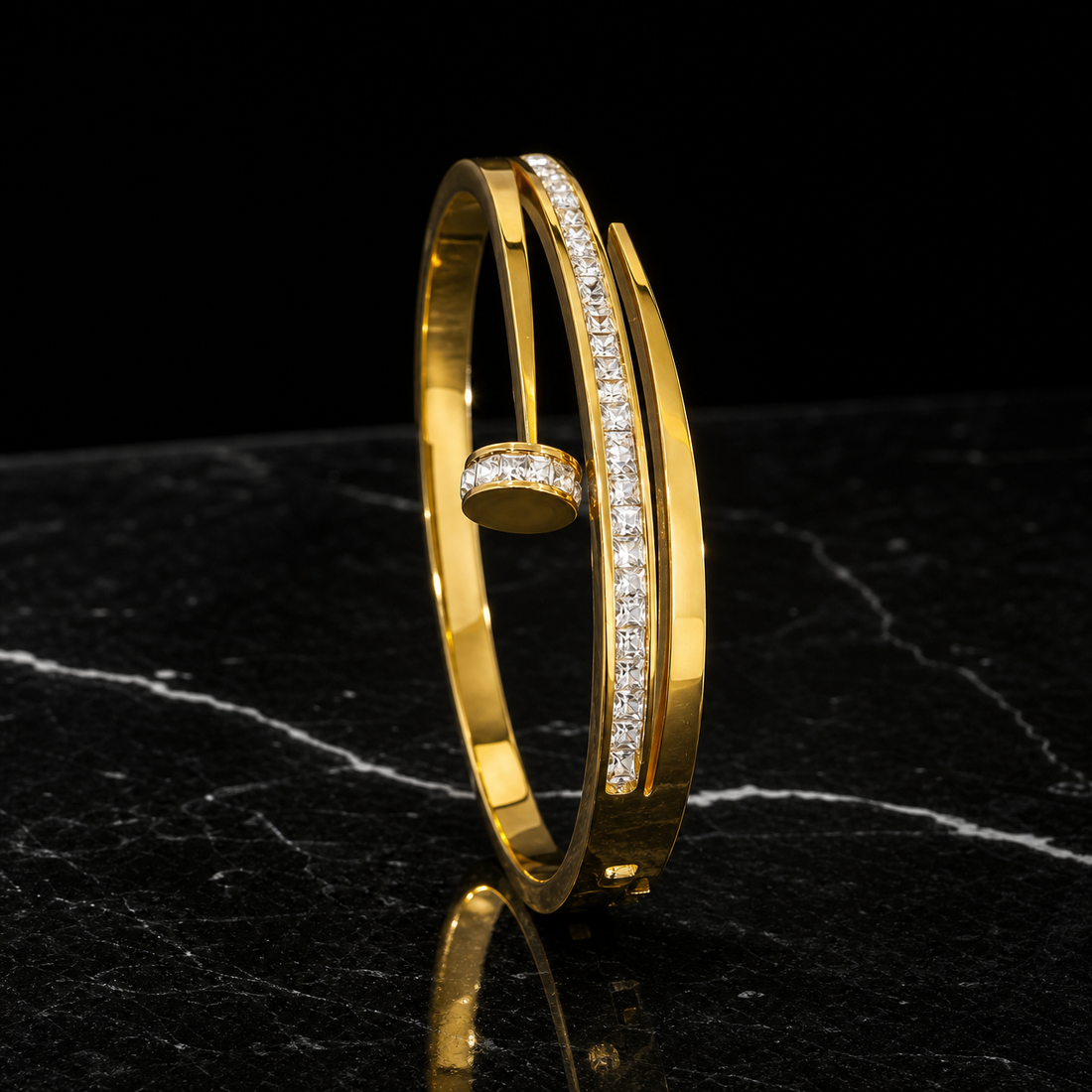 A single rigid bangle in polished yellow gold, high-shine finish. The band is a flat cross-section strip roughly one-twentieth of the outer diameter in width, even all the way round with no swelling. It is an open cuff: the band ends overlap and cross past each other, leaving a gap approximately equal to the band width, with one end terminating in a round flat disc end cap edged with small round colourless stones in a pavé-style setting.