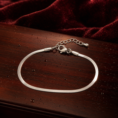 One chain bracelet in silver-tone metal with a bright polished finish. Construction is a single continuous strand of flat, flexible snake (herringbone-style) chain of narrow, uniform gauge, with no branches, joins or secondary strands along its run. The largest component is the lobster clasp; the main chain run is approximately 45 to 50 times the clasp's width.