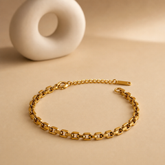 One wrist-worn chain bracelet in a warm yellow-gold-toned metal with a polished, reflective finish. It is a single continuous strand of medium-gauge rectangular brick-link (panther-style) chain, each link a flat rounded-corner bar segment articulated to the next, with no branches, charms, stations, beads or stones anywhere along the run. The main chain run measures approximately 25 to 30 times the width of one link.
