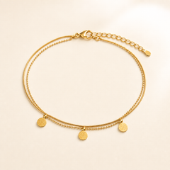One anklet in yellow-gold-tone metal with a polished finish. It is built as two parallel fine strands joined at shared end fittings: a smooth snake-type chain and a slightly heavier beaded/ball chain of small linked spheres, both of fine gauge. The chain run is roughly twenty times the width of the largest component, and the short extender at the far end is about one-sixth of the main chain length.
