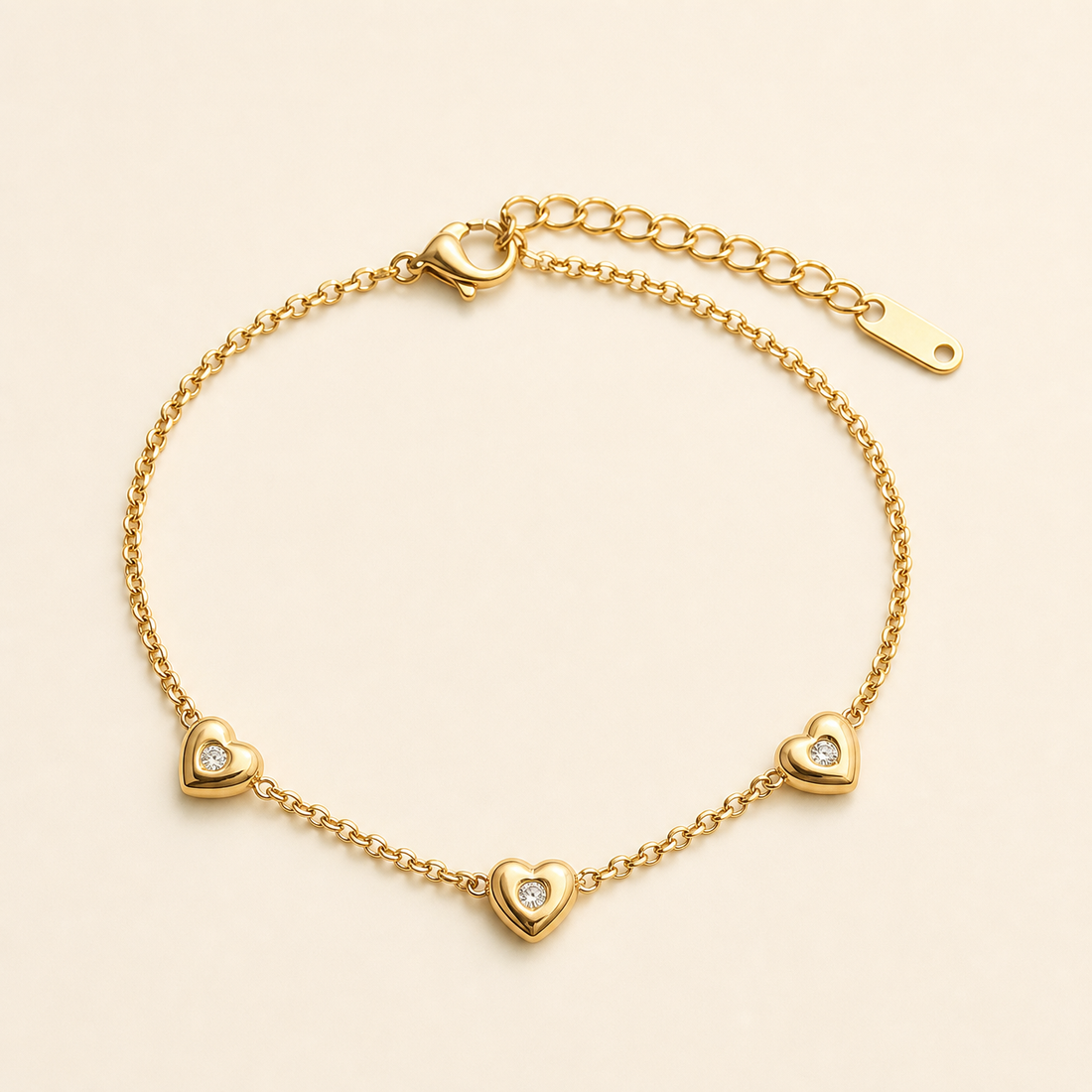 One anklet in yellow-gold-toned metal with a polished finish. It is a single-strand fine cable chain of small round links. A working lobster clasp is visible at one end, joined to an extender of larger open oval links roughly one quarter the length of the main chain, terminated by one elongated flat drilled tag. The main chain run is approximately twenty-five times the width of the largest component.