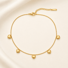 One anklet in yellow-gold-tone metal with a polished finish. It is a single-strand, fine-gauge ball chain (small round bead links) forming one closed loop with no branches. The chain run measures roughly 30–35 times the width of its largest component, and the curb-link extender chain is about one quarter the length of the main chain. A working lobster clasp is present.