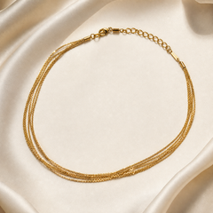 One multistrand necklace, in yellow-gold-coloured metal with a bright polished, finely textured finish. It comprises exactly six very fine, closely gauged chain strands, each appearing as a narrow textured link chain; the strands run independently in parallel between two cylindrical end caps, with no branches, cross-connections, decorative stations or centre junction.