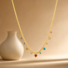 One necklace, gold-tone metal with a polished finish, built as a single flat herringbone chain of fine, tightly woven links. The chain run is approximately 30 times the width of the largest charm; no extender chain is present, and no working clasp is visible in the view. Eleven bezel-set dangling charms hang from the chain at uneven intervals, each mounted through a small fixed bale so it swings below the strand.