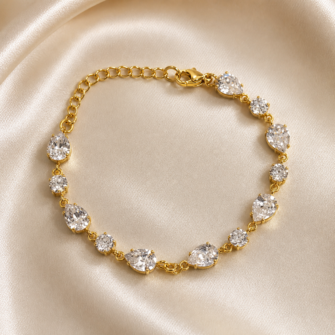 One chain bracelet in yellow-gold-tone metal with a bright polished finish. Single-strand construction: a short run of small round cable chain links forms an extender at one end, meeting a lobster clasp with a flat rectangular metal terminal tag; the clasp connects to the gem-set main run. The chain run measures roughly twenty times the width of the largest component, and the extender chain is about one quarter of the main run's length; a working lobster closure is visible.