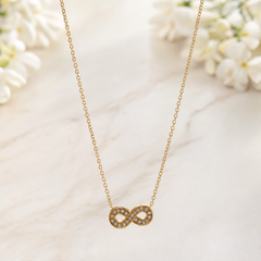 One necklace, gold-tone metal with a polished finish. Construction is a single strand of fine-gauge cable chain with small oval links, running unbroken from the concealed upper ends down to a single fixed central pendant; the clasp and any extender are partly obscured and cannot be confirmed, so no working closure is clearly visible. The chain run is approximately 30 times the width of the pendant, indicating neck length; any extender, if present, is hidden and its length cannot be stated.