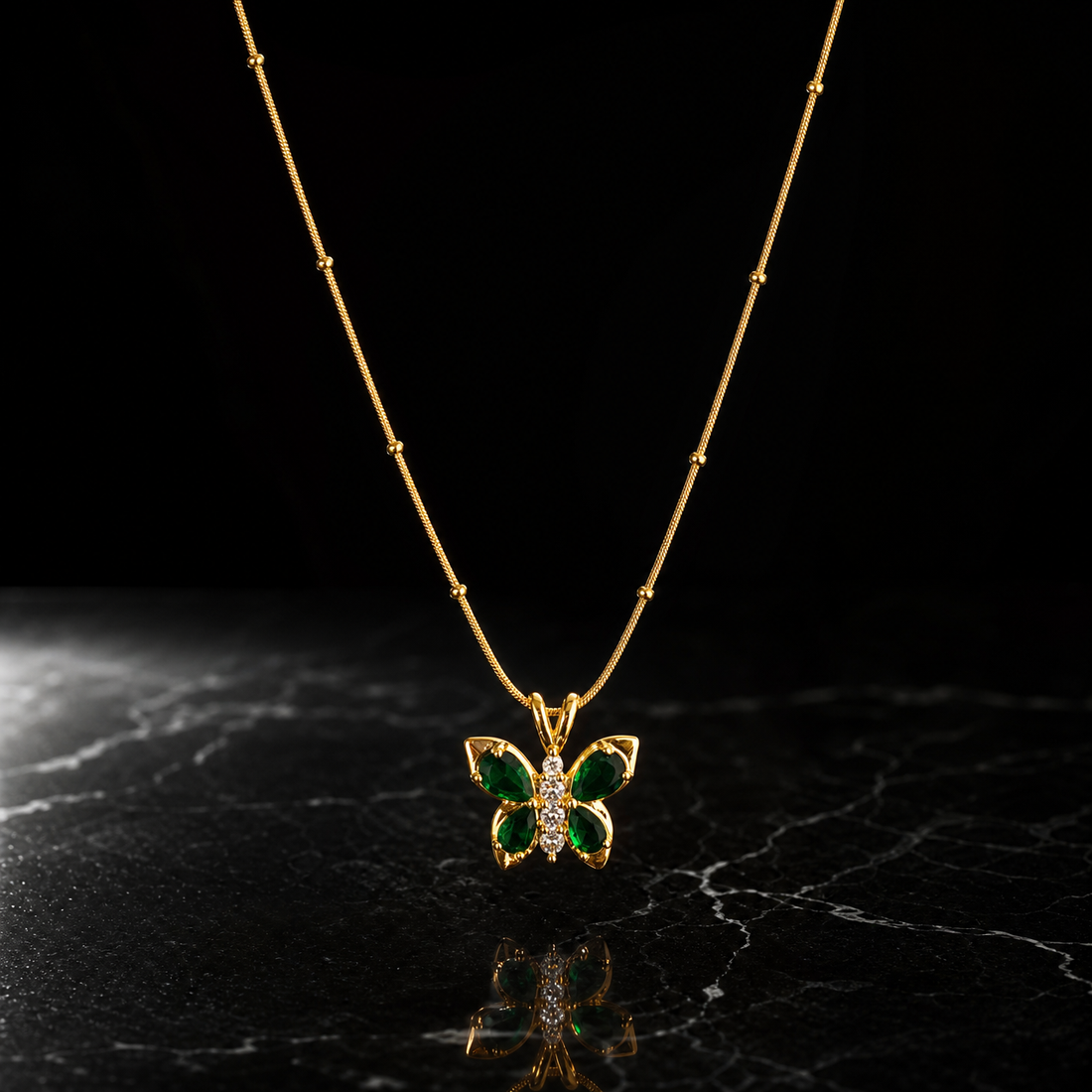A single pendant necklace in yellow-gold-toned metal with a polished finish. It is one strand of fine snake chain of narrow gauge, interrupted by small round gold bead stations fixed at irregular intervals along the run; the chain exits the frame at both ends, so the full run is partly obscured and no clasp or extender is visible. The visible chain run is roughly twelve to fourteen times the width of the pendant, the largest component.