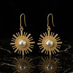 Two earrings of one coordinated design. Gold-tone metal with polished French hook ear wires of moderate length and fine gauge; each hook joins through a small jump ring to a single rigid sunburst drop, giving one hanging section that swings from the fitting. Overall drop is about twice the widest sunburst diameter.