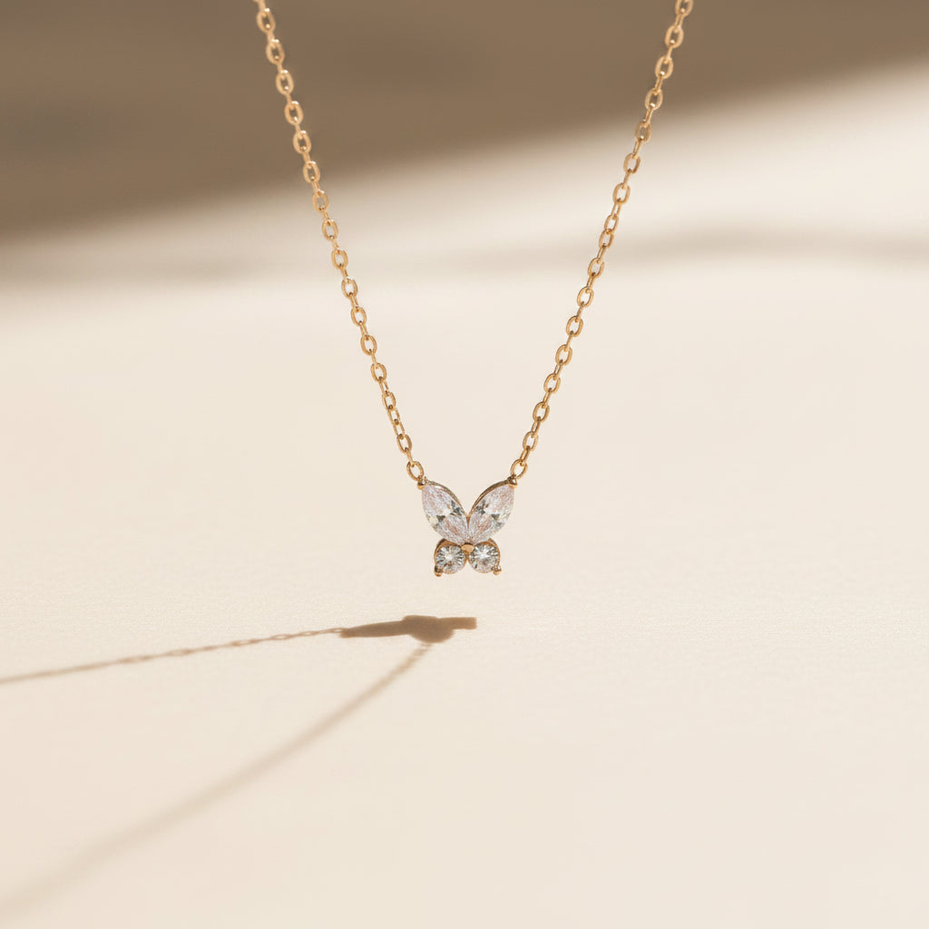 Butterfly-shaped pendant necklace on a chain against a plain background