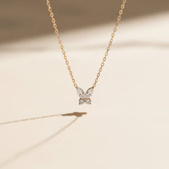 Butterfly-shaped pendant necklace on a chain against a plain background