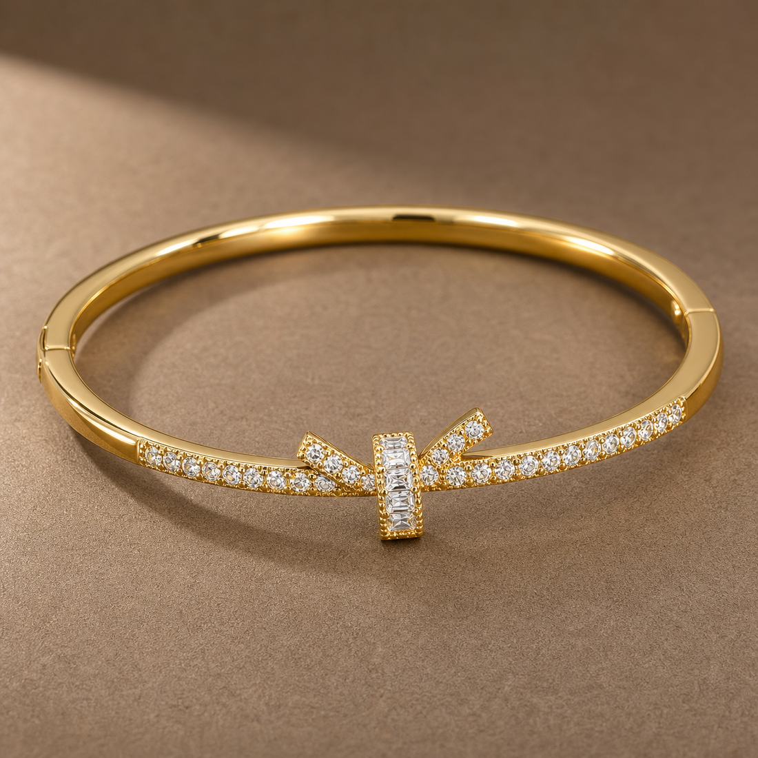 Gold-tone 316L stainless steel bangle with a crystal-set band and a baguette-stone T-bar centre, on a flat surface
