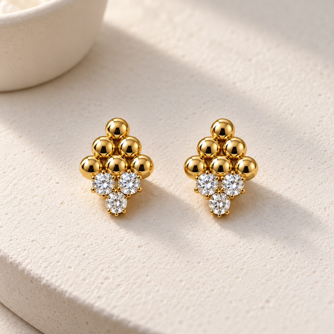 Gold-tone 316L stainless steel stud earrings with a cluster of gold ball beads and three clear crystals, a pair