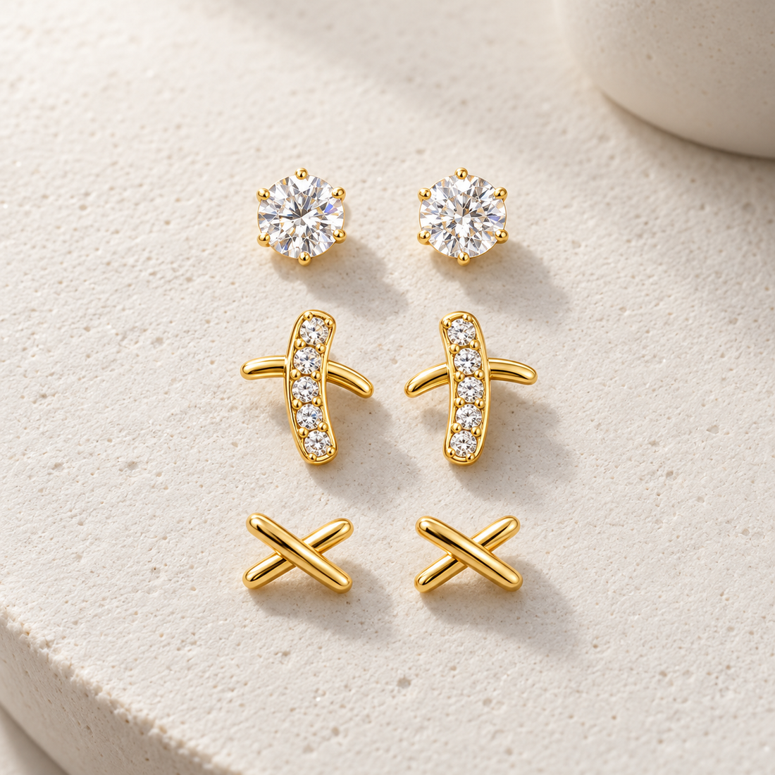Gold-tone 316L stainless steel earrings set of three: round crystal studs, crystal-set bar studs, and plain crossed studs