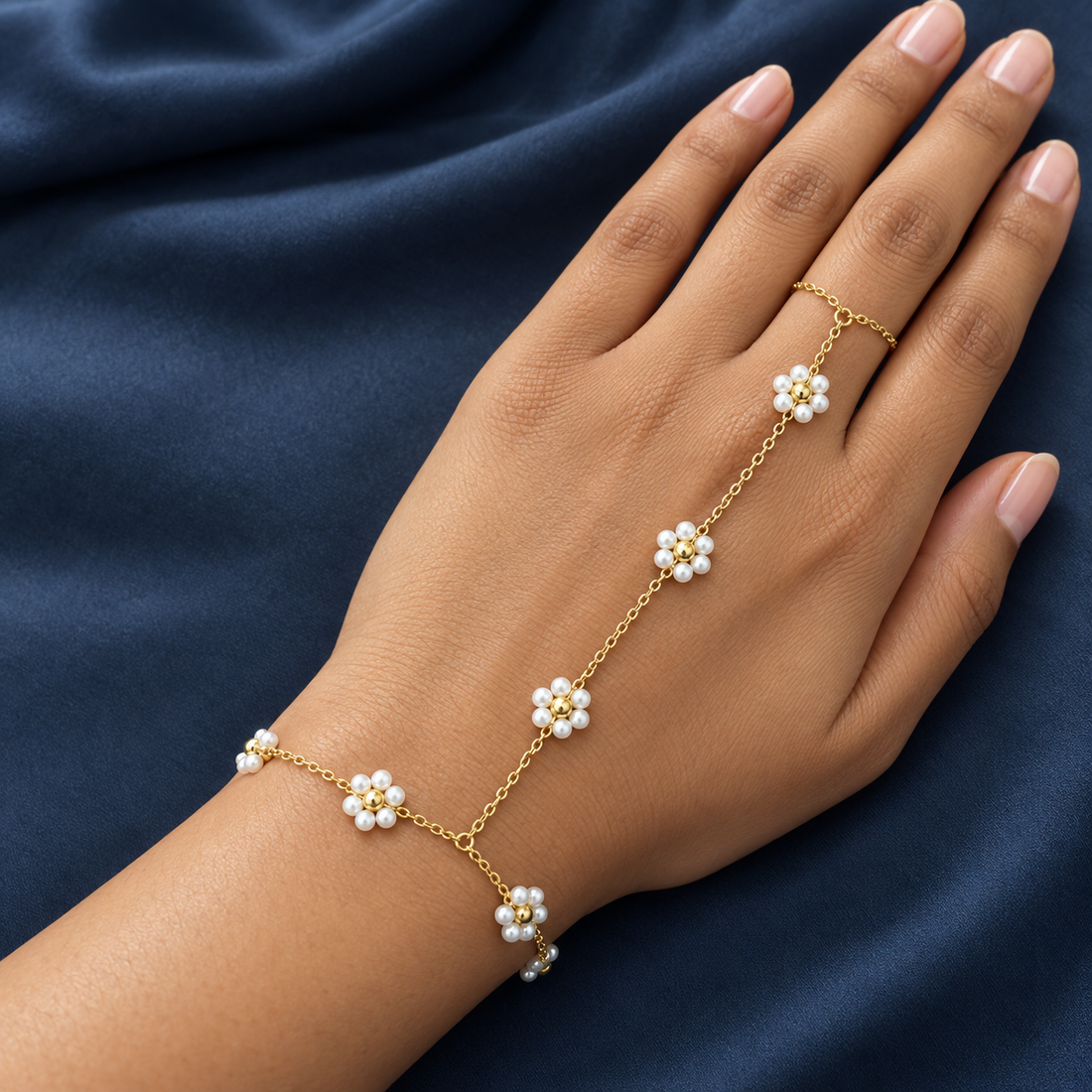 Gold-tone 304 stainless steel hand chain with pearl and gold-bead flower motifs on a fine link chain, worn on a hand with a ring link over one finger