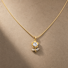 Gold-tone 316L stainless steel snake chain necklace with a flower pendant set with a round clear stone and two marquise leaves, worn at the neck