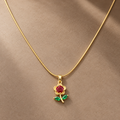 Gold-tone 316L stainless steel flower pendant necklace with a red round stone centre and green marquise leaves on a thin snake chain, worn at the neck