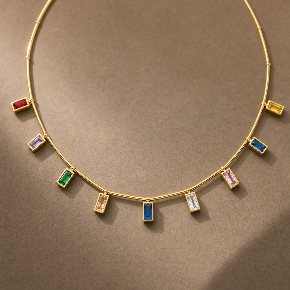Gold-tone 304 stainless steel necklace with a thin rigid bar chain and nine bezel-set rectangular stones in red, green, blue, pink, yellow and white