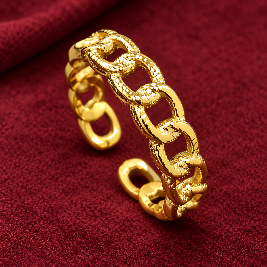 Gold-tone 304 stainless steel open ring with interlocking textured curb links, shown on a red fabric surface