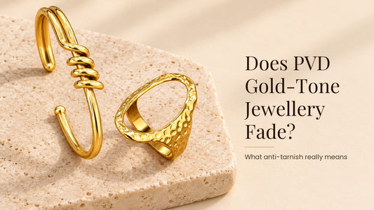 Does PVD Gold-Tone Jewellery Fade?. A glossy gold-tone stainless steel cuff and ring on a pale cream stone slab