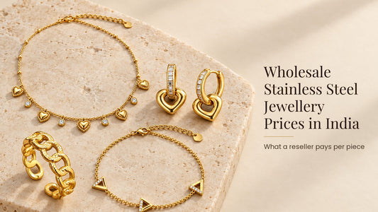Wholesale Stainless Steel Jewellery Prices in India. Gold-tone stainless steel necklace, earrings, ring and bracelet on a pale cream stone slab