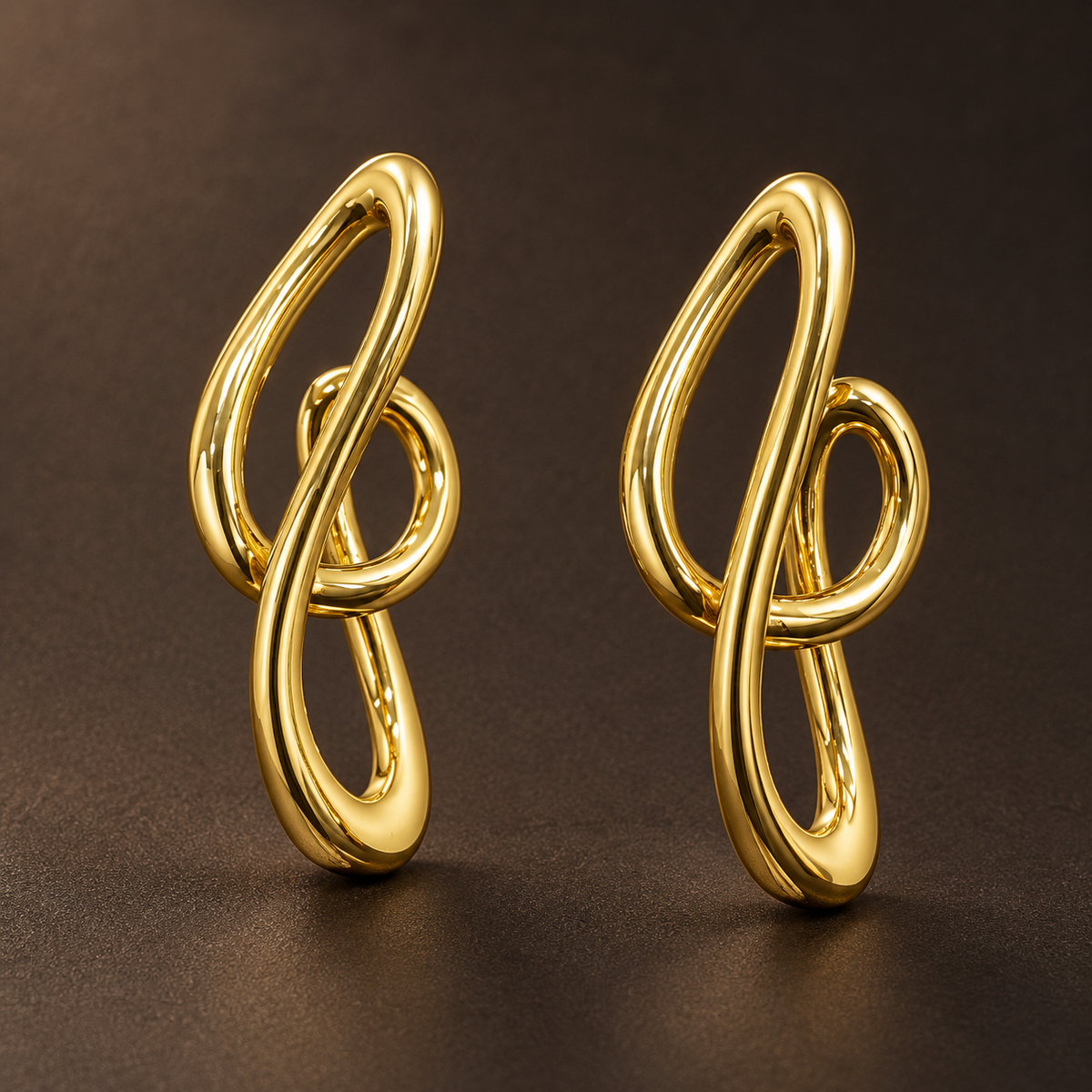 Gold-tone 304 stainless steel earrings in a pair, each a looped knot-shaped wire design with a smooth polished finish, on a dark brown background