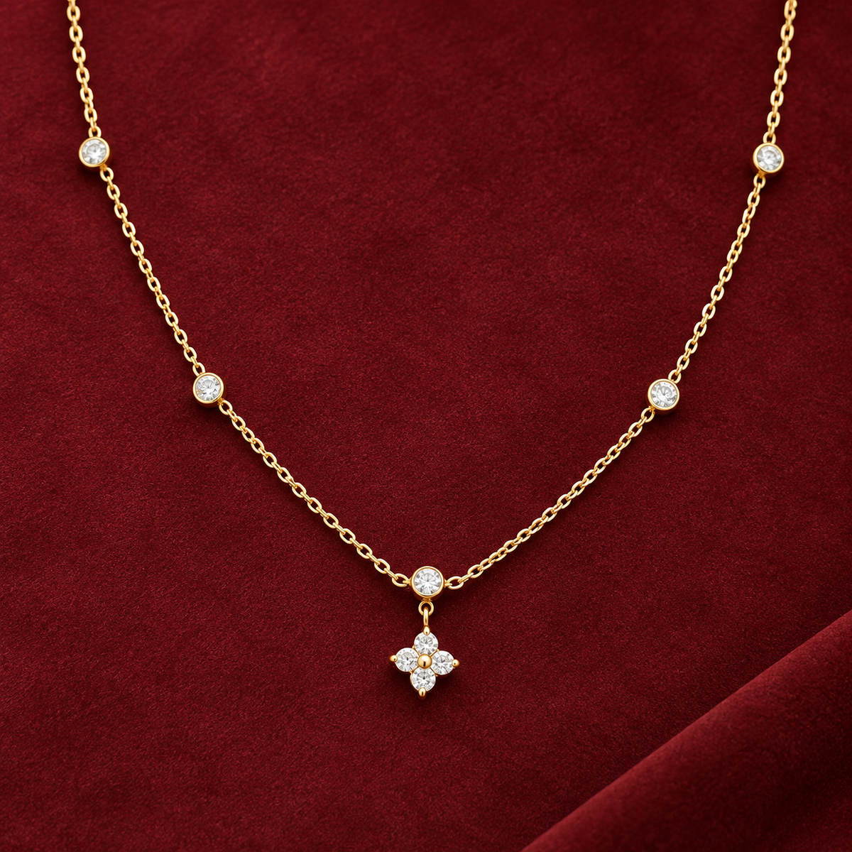 Gold-tone 316L stainless steel necklace with a fine chain, bezel-set crystals along its length and a four-stone flower pendant, shown laid flat