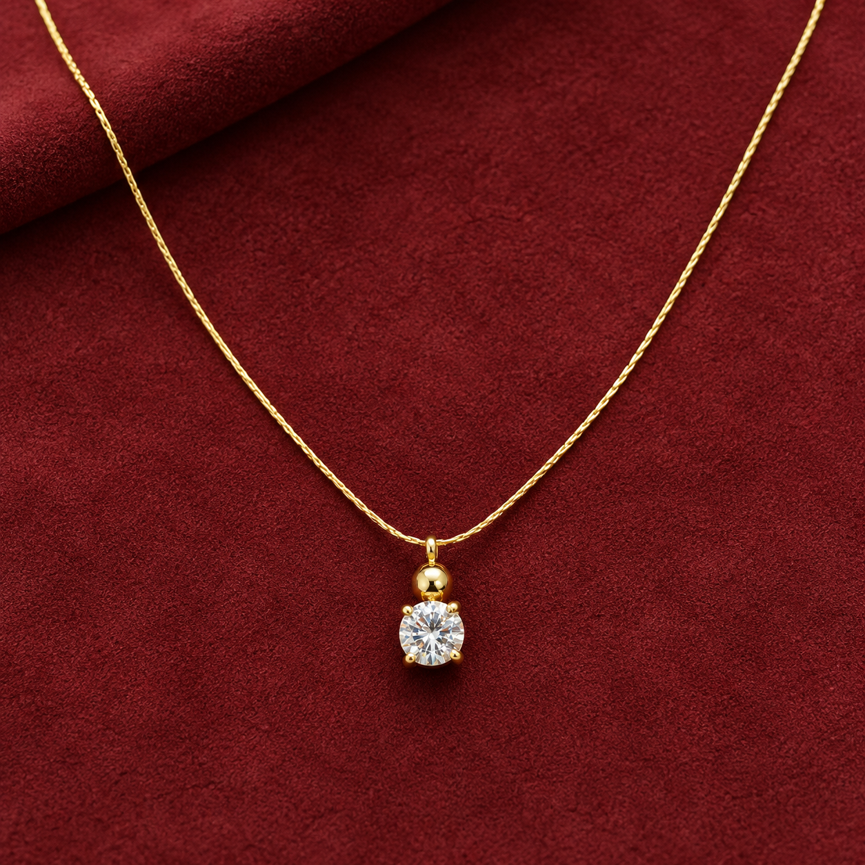 Gold-tone 316L stainless steel necklace with a fine twisted chain and a pendant of a small ball above a round clear stone in a four-claw setting