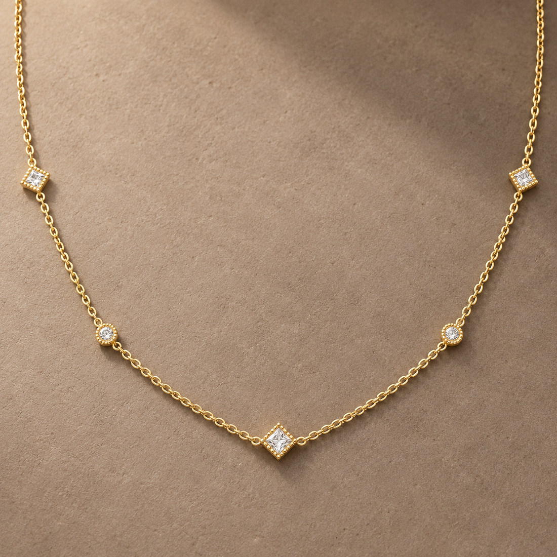 Gold-tone 316L stainless steel necklace with a fine cable chain and five clear stones in milgrain settings, worn at the neckline