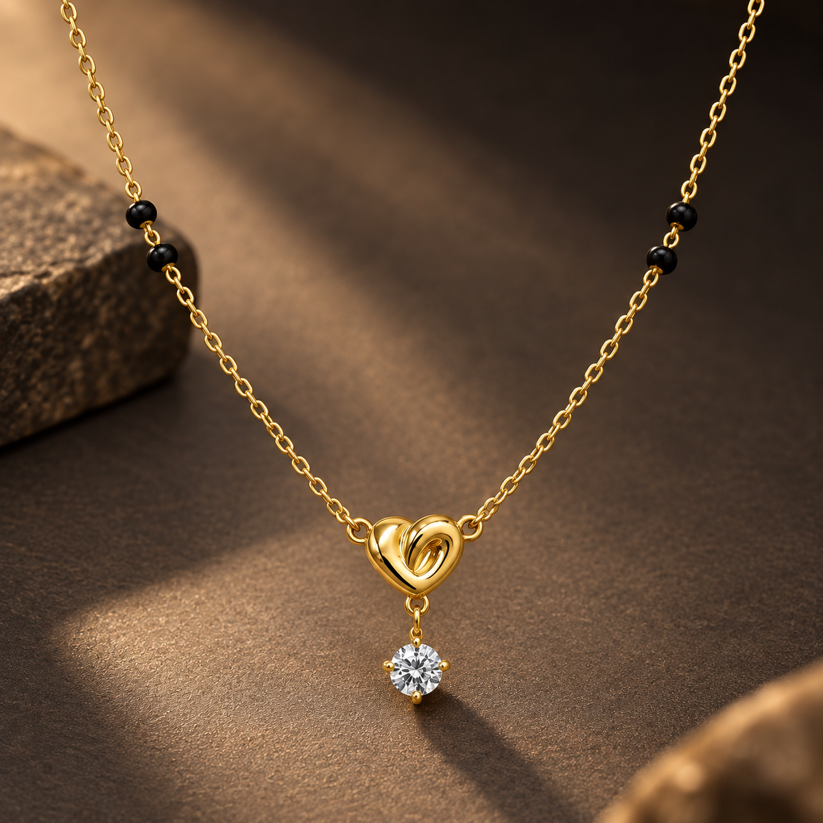 Gold-tone 316L stainless steel mangalsutra necklace with black beads, a heart-shaped pendant with a twisted loop and a hanging round clear stone