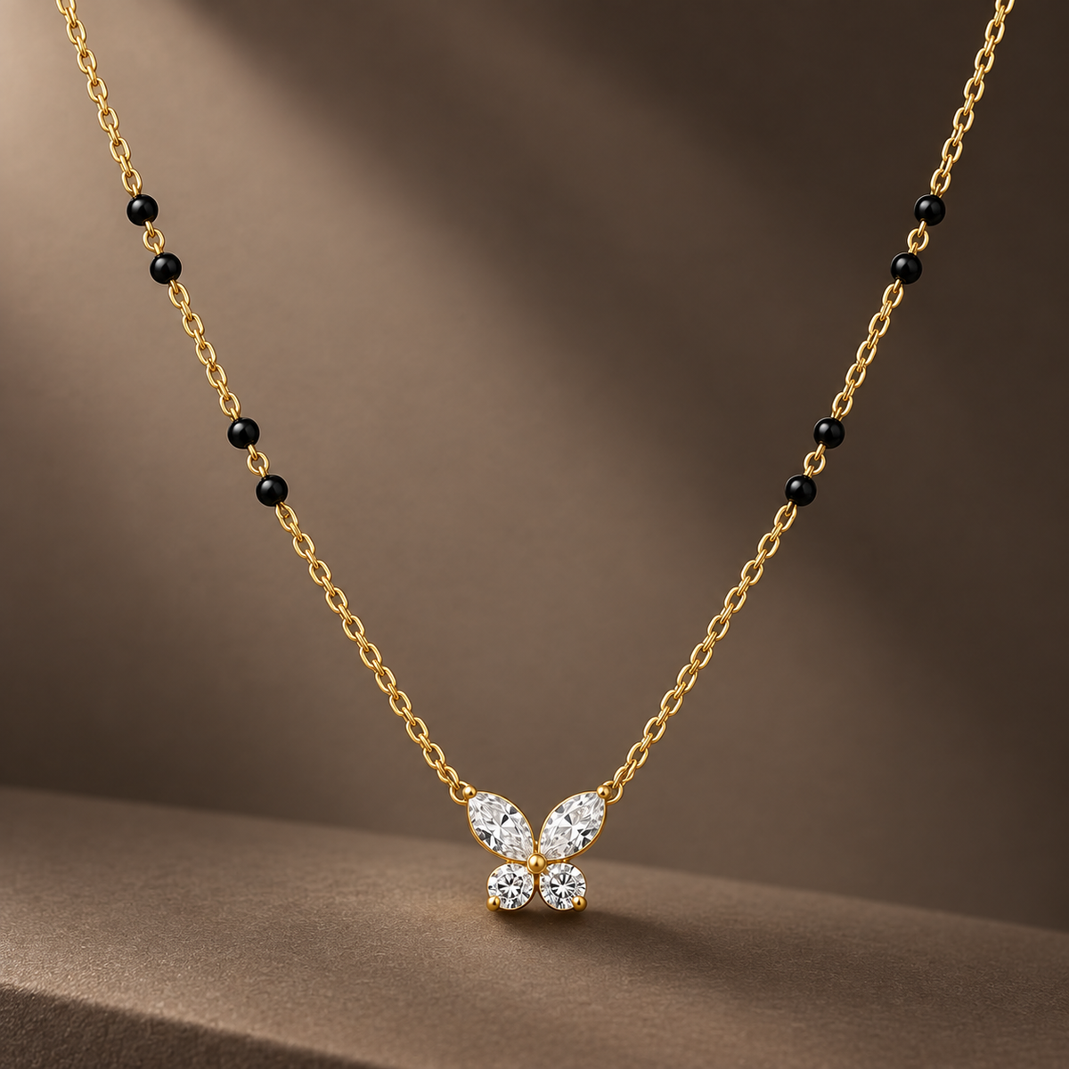 Gold-tone 316L stainless steel mangalsutra necklace with black beads and a butterfly pendant of clear stones on a cable chain