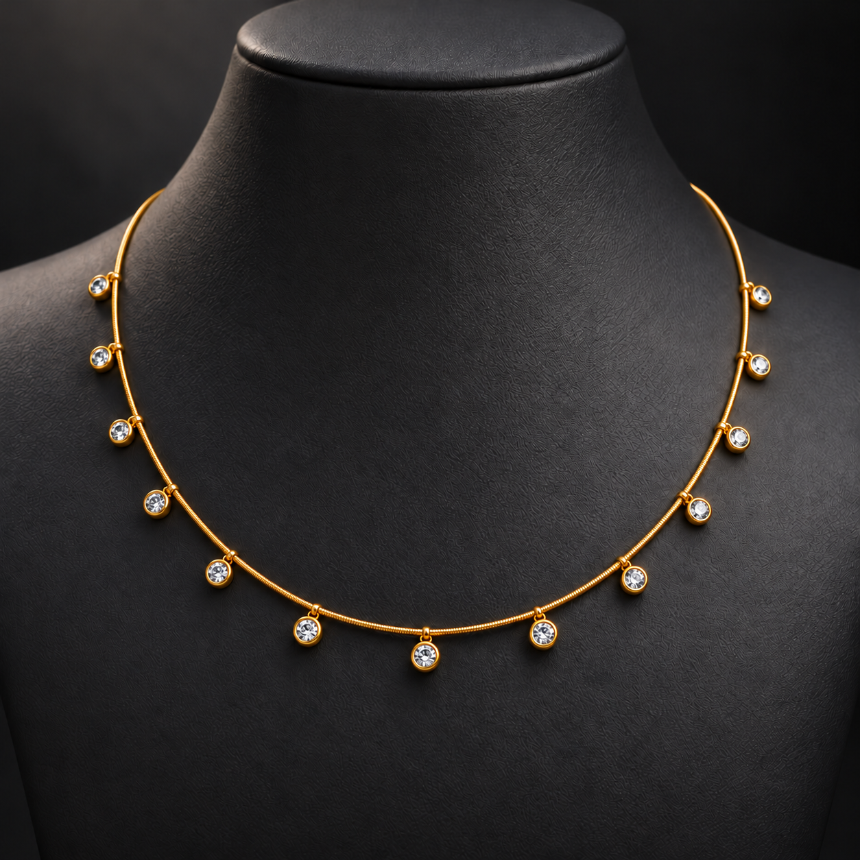 Gold-tone 304 stainless steel necklace with a round snake chain and clear stones in bezel settings hanging at intervals, worn on a dark bust