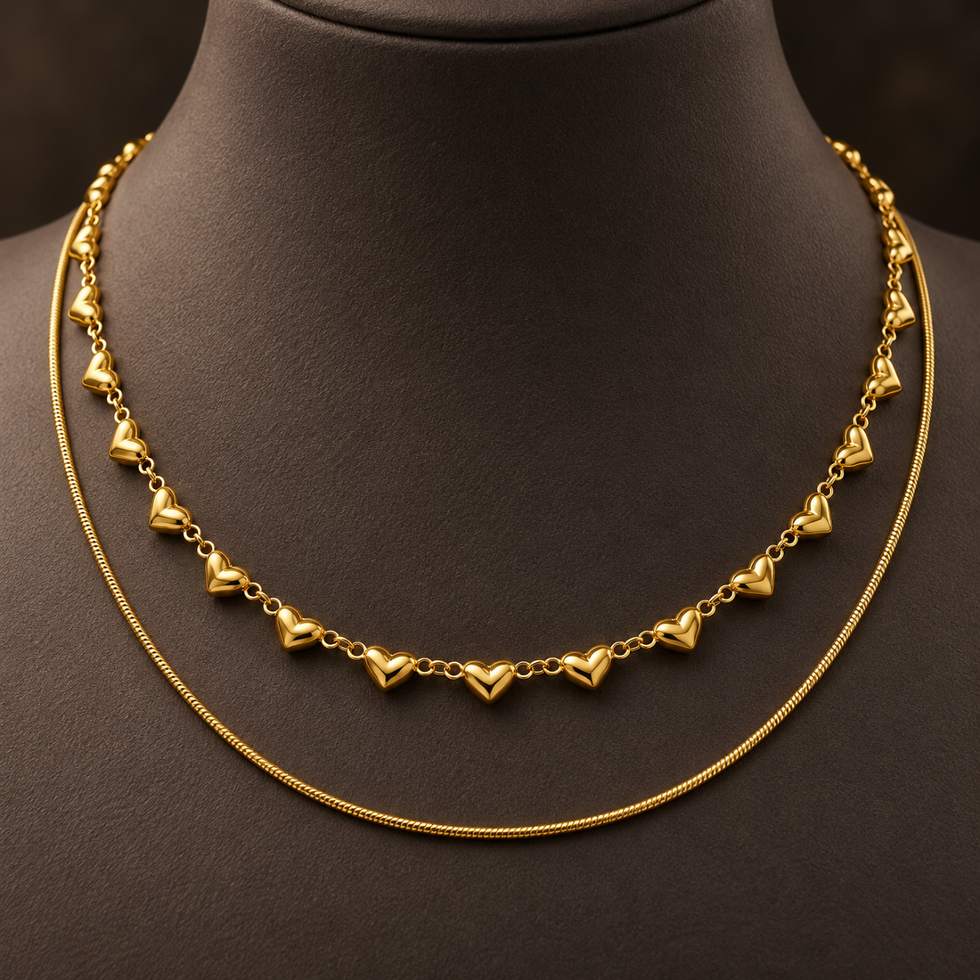 Gold-tone 316L stainless steel two-piece necklace set: a heart-motif chain with puffed hearts on a link chain, and a thin snake chain, worn on a neck form