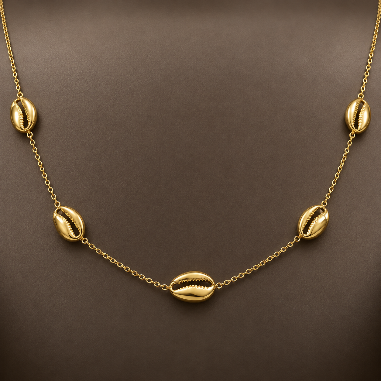 Gold-tone 316L stainless steel necklace with five cowrie shell motifs spaced along a fine cable chain, worn on a neck