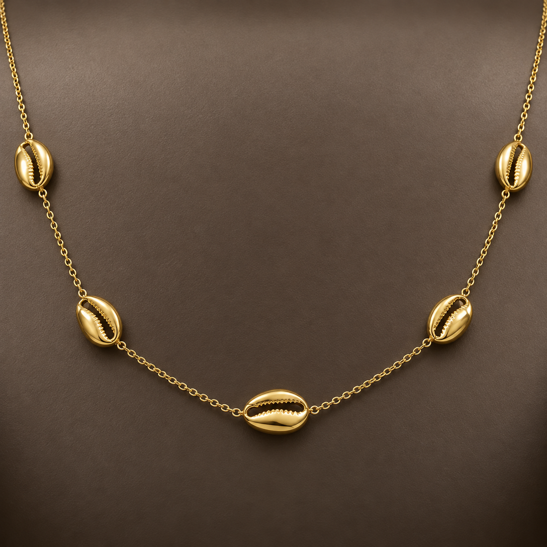 Gold-tone 316L stainless steel necklace with five cowrie shell motifs spaced along a fine cable chain, worn on a neck