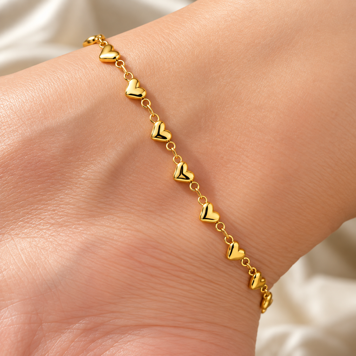 Gold-tone 316L stainless steel bracelet with small puffed heart links joined by open rings, worn on a wrist