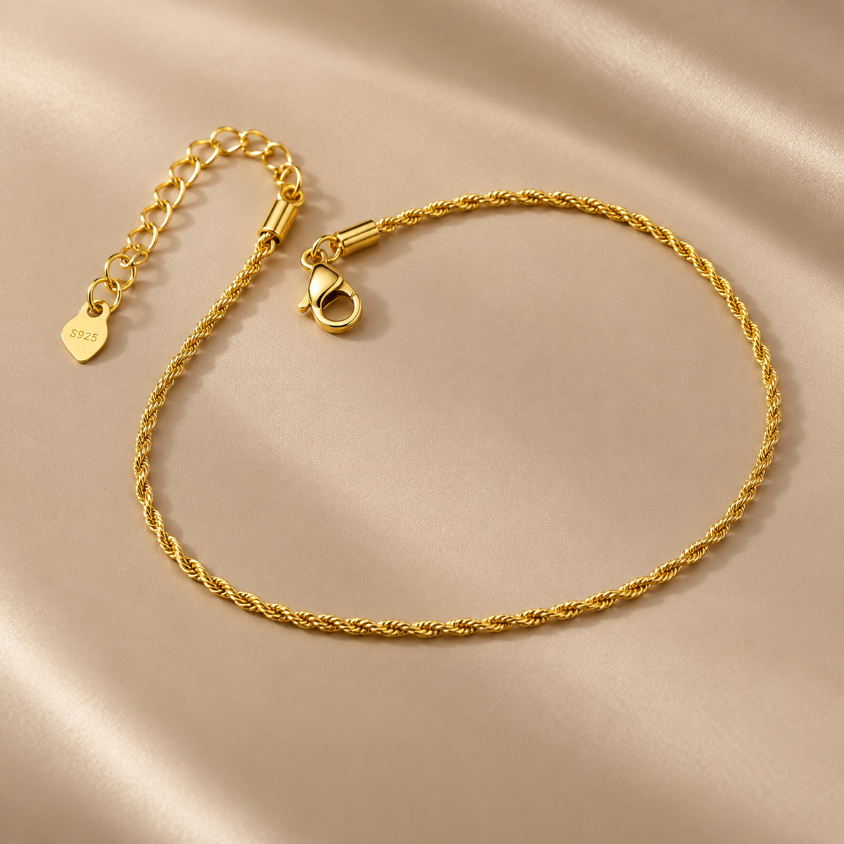 Gold-tone 316L stainless steel rope-chain anklet with a lobster clasp and an extension chain, laid flat on a satin cloth