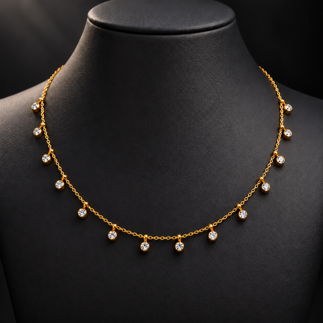Gold-tone 304 stainless steel necklace with a fine cable chain and round clear stones in bezel settings hanging along the front, shown on a display bust