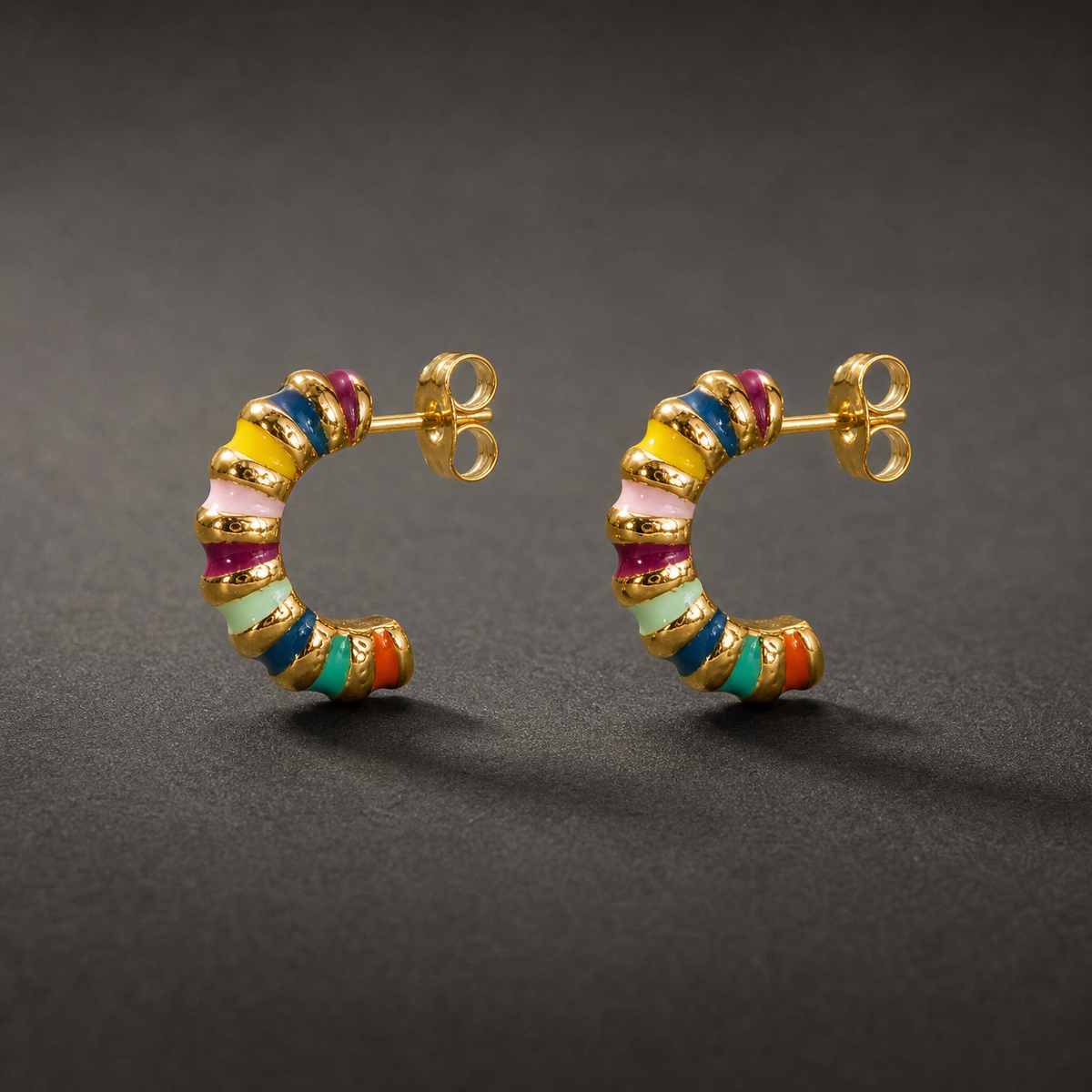 Two ear-worn earrings, a pair of small half-hoop (J-hoop) studs in gold-tone metal with a polished finish. Each fits with a post and butterfly back, the post slim and standard gauge, roughly one and a half times the hoop's width in length. Overall drop is approximately one and a half times the widest point of the hoop.