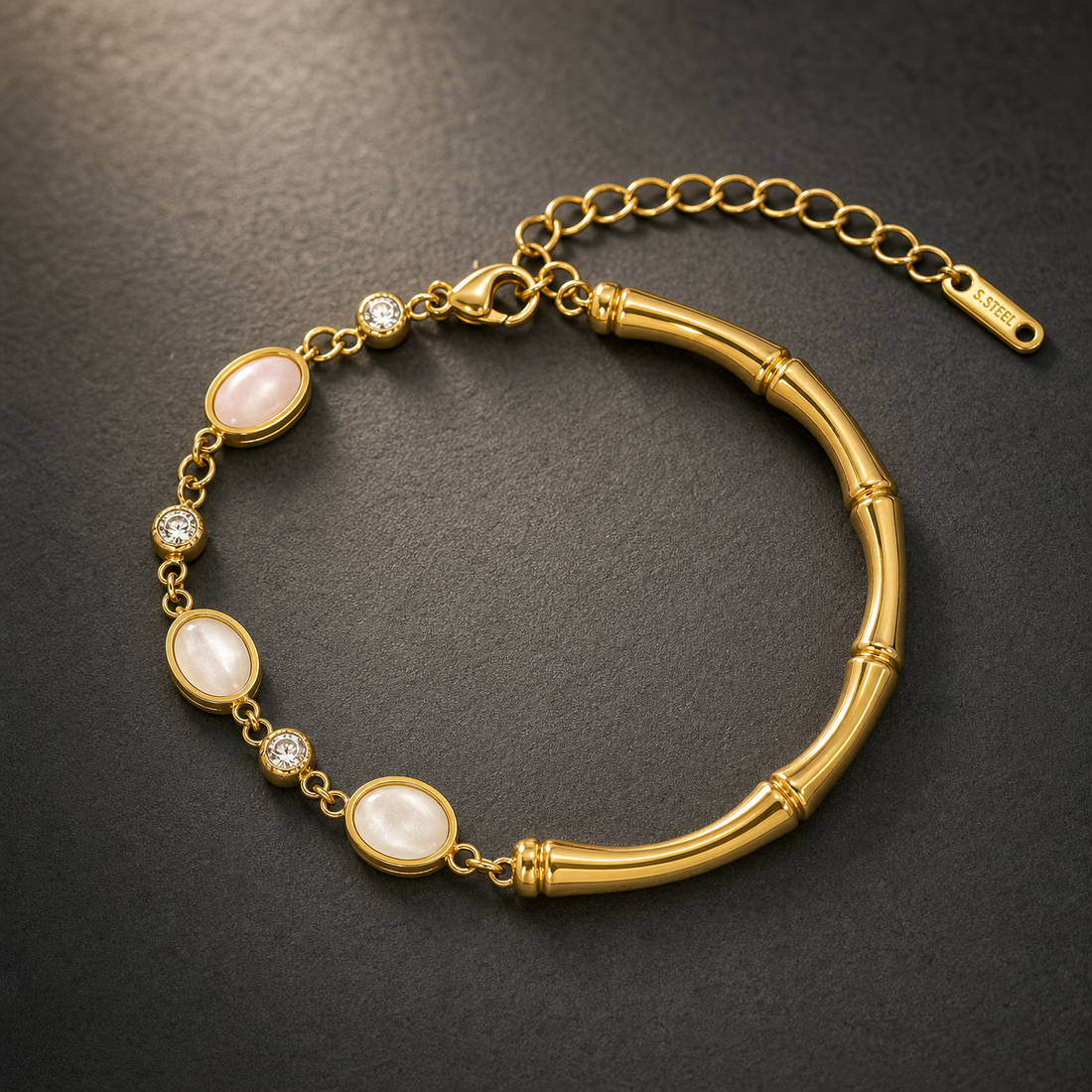 One gold-toned chain bracelet with a polished finish. It is a single-strand flexible piece: one half is a fine oval-link chain of small gauge carrying alternating bezel-set stations, and the other half is a solid curved bamboo-segmented bar forming a rigid section, connected at both ends by small jump rings. The total chain run is approximately twelve times the width of the largest oval component; the extender chain is roughly one third of the main chain length. A working lobster clasp is visible.