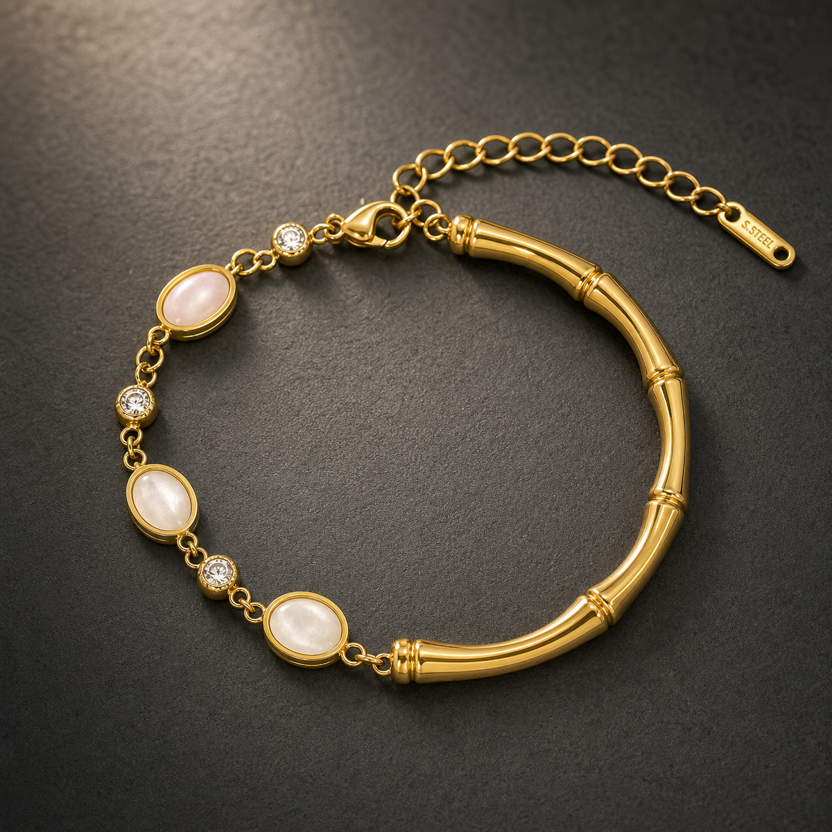 One gold-toned chain bracelet with a polished finish. It is a single-strand flexible piece: one half is a fine oval-link chain of small gauge carrying alternating bezel-set stations, and the other half is a solid curved bamboo-segmented bar forming a rigid section, connected at both ends by small jump rings. The total chain run is approximately twelve times the width of the largest oval component; the extender chain is roughly one third of the main chain length. A working lobster clasp is visible.