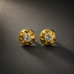 Two ear-worn stud earrings of one design, in yellow-gold-coloured metal with a polished and textured finish. Each is a single rigid domed disc, roughly as deep as it is wide, with no articulation or hanging sections. The fitting is a post and back; the posts are partly obscured, so length and gauge cannot be confirmed.